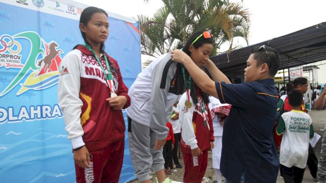 Ketua KONI Sulsel, Yasir Machmud mengalungkan medali, Rabu (26/10). 
