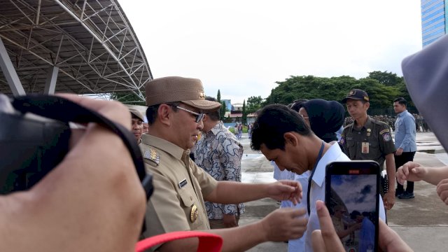 Wali Kota Makassar, Moh ramdhan Pomanto memasang atribut pada salah satu satlinmas Pemliu dalam apel kesiapan Pemilu 2024 di Makassar. Foto: harian.new/sinta