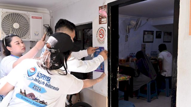Salah satu tim menempelkan flyer edukasi CBP Rupiah di salah satu rumah makan di Kota Makassar (12/7). (Foto: BI Sulsel)