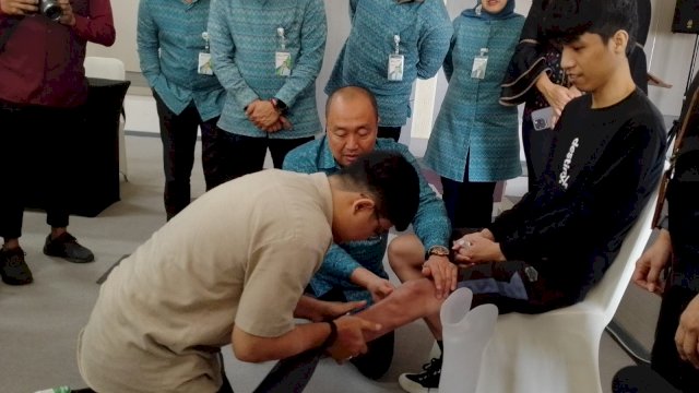Resky Lubis (kaos hitam, duduk di kursi) saat dipasangi kaki palsu. (Foto: Gita/HN)