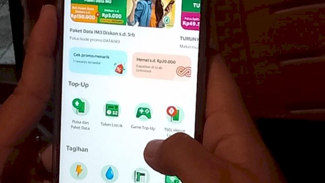 Riska Fahyuni saat membuka aplikasi Grab untuk membeli data Indosat. (Foto: Gita/HN)