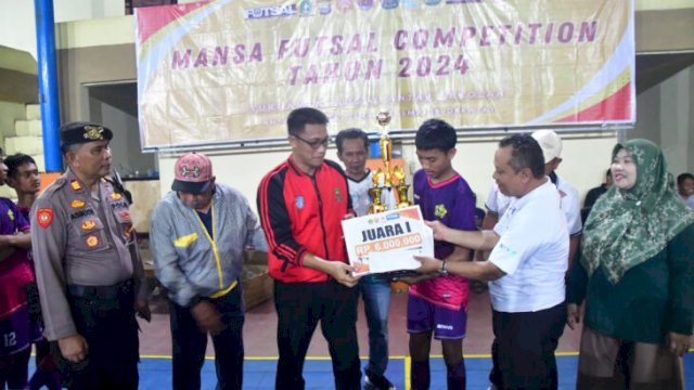 Asisten 1 Setdakab Sinjai, Andi Irwansyahrani Yusuf, menyerahkan penghargaan kepada juara Mansa Futsal Competition 2024 di Lapangan Futsal Semi Indoor Sinjai || humas 