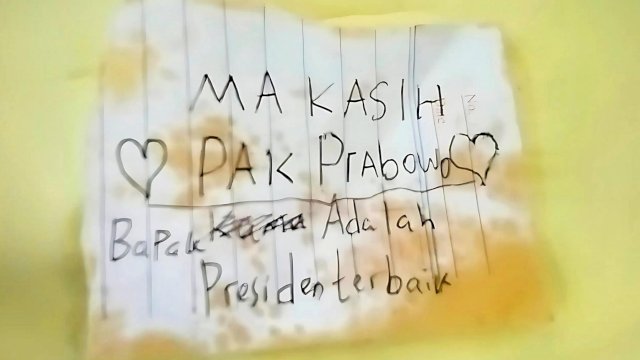 Seorang siswa SD menulis pesan ucapan terima kasih di selembar kertas kecil sebagai apresiasi atas program Makan Bergizi Gratis ||X@KSPgoid