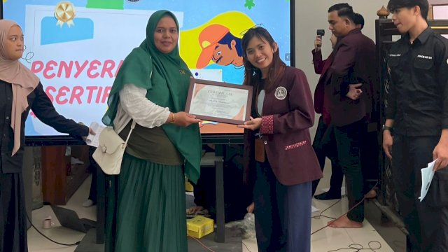 Dosen UC Makassar, Novika Ayu Triani (kanan) menerima plakat dari SMA 11 Makassar. 