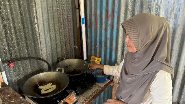 Andi Hasriani (51) sedang memasak dengan kompor biogas. Biogas tersebut dimanfaatkan sebagai bahan bakar alternatif untuk kebutuhan memasak sehari-hari, menggantikan tabung gas. (Foto: PLN)