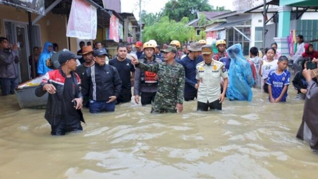 Bupati Bone Andi Asman Sulaiman berjalan kaki menembus banjir untuk meninjau langsung rumah warga terdampak di Kelurahan Panyula. (ho_doc:basarnasmks) 