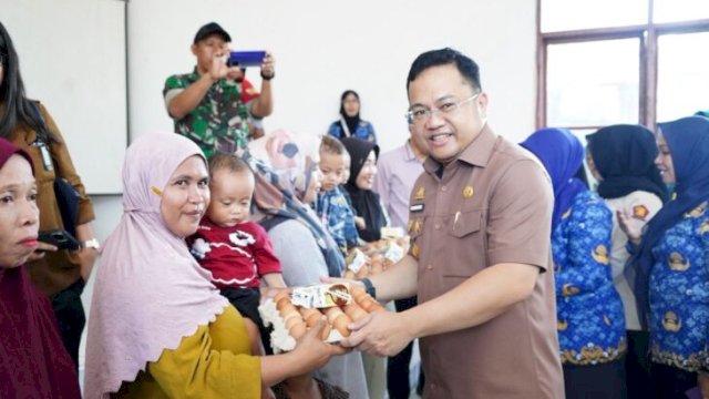 Wakil Bupati Gowa, Darmawangsyah Muin (tengah), menyerahkan paket makanan bergizi kepada perwakilan ibu hamil dan balita di Aula Kantor Kecamatan Bajeng, Selasa (2/6/2026). (foto_humaskab) 